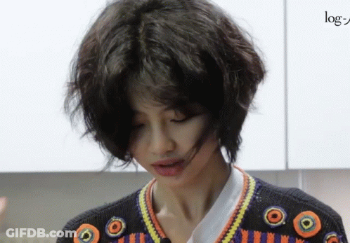 A Woman With Short Hair Is Wearing A Sweater With Circles On The Sleeves GIF
