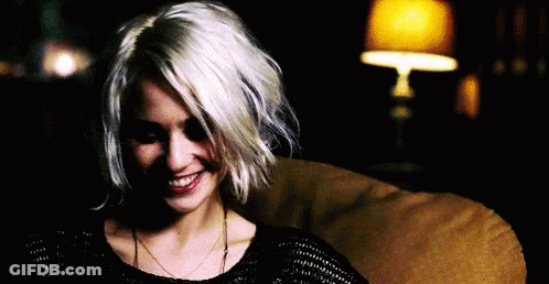 A Woman With Short White Hair Is Sitting On A Couch And Smiling . GIF