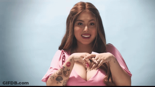 A Woman With Tattoos On Her Arm Making A Heart Shape With Her Hands GIF