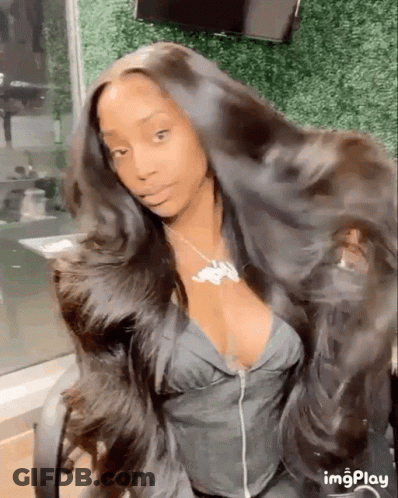 A Woman With Very Long Hair Is Sitting In A Chair And Looking At The Camera . GIF