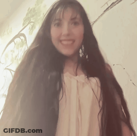 A Woman With Very Long Hair Is Smiling And Looking At The Camera GIF