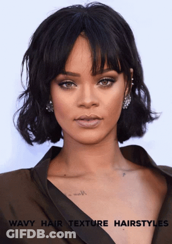 A Woman With Wavy Hair And A Tattoo On Her Chest GIF