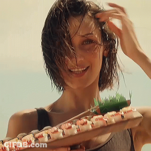 A Woman With Wet Hair Is Holding A Tray Of Sushi GIF