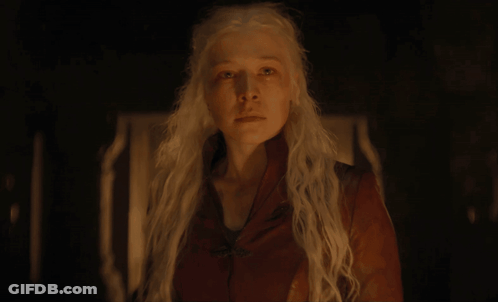 A Woman With White Hair And A Red Jacket Looks At The Camera GIF