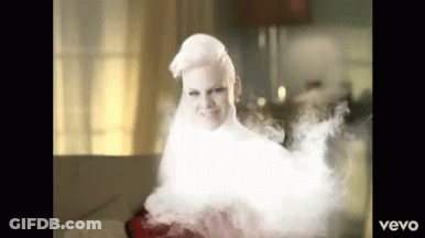A Woman With White Hair Is Surrounded By Smoke And The Word Vevo Is On The Bottom Right GIF