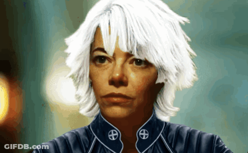 A Woman With White Hair Is Wearing A Blue Jacket With A Symbol On The Collar GIF