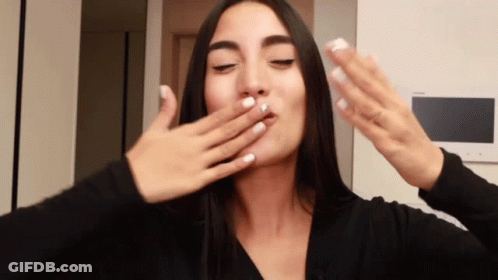 A Woman With White Nails Is Covering Her Mouth With Her Hand GIF
