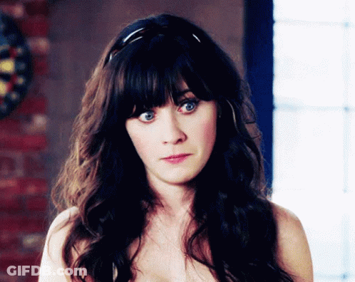 A Woman Without A Shirt Is Looking At The Camera With A Dart Board In The Background GIF