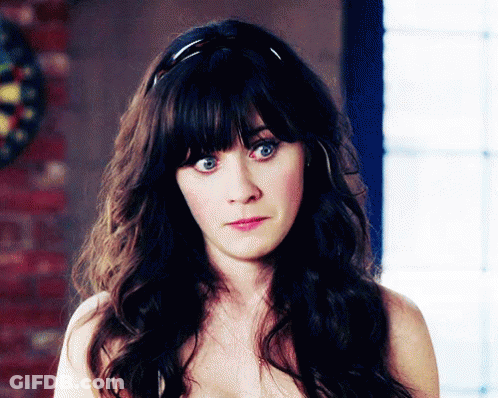 A Woman Without A Shirt Is Looking At The Camera With A Dart Board In The Background GIF