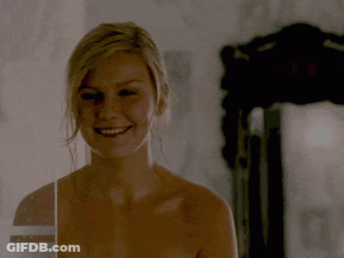 A Woman Without A Shirt Is Smiling And Looking At The Camera GIF