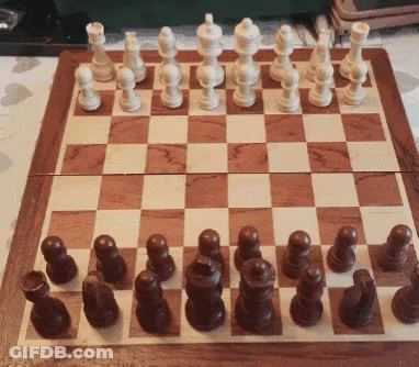 A Wooden Chess Board With White And Brown Chess Pieces On It GIF