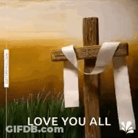 A Wooden Cross With A White Ribbon Tied Around It . GIF