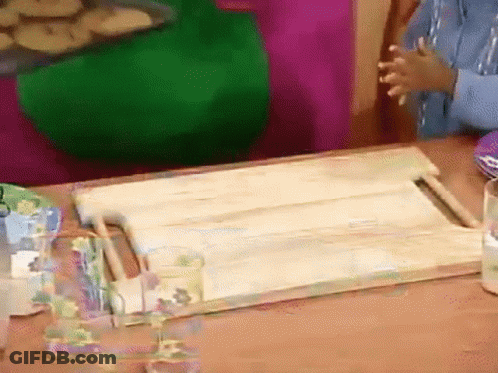 A Wooden Cutting Board Is Sitting On A Table GIF