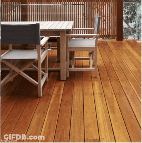 A Wooden Deck With A Table And Chairs And A Fence Behind It GIF
