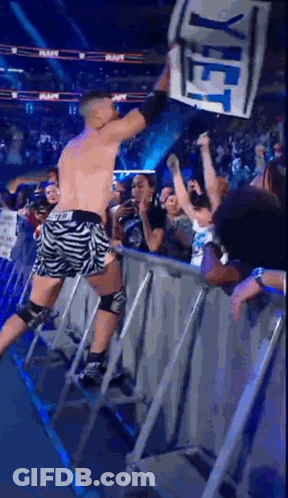 A Wrestler Holds Up A Sign That Says Yet In Front Of A Crowd GIF