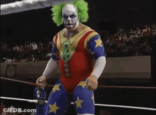 A Wrestler In A Clown Costume Is Standing In A Ring GIF