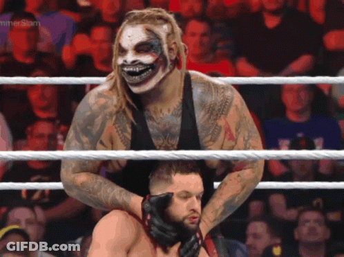 A Wrestler In A Clown Mask Is Holding Another Wrestler In A Ring With A Hammerslam Logo In The Background GIF