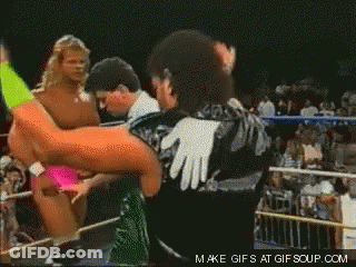 A Wrestler In A Green And Black Outfit Is Standing In A Ring GIF