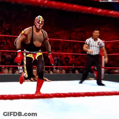 A Wrestler In A Mask And Boxing Gloves Is Running In A Ring With A Referee GIF