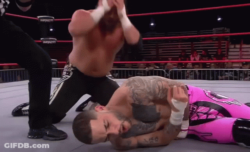 A Wrestler In A Pink Outfit Is Laying On The Ground GIF