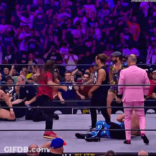 A Wrestler In A Pink Suit Stands In The Ring GIF