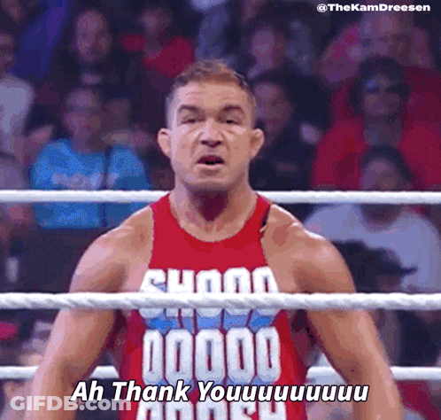 A Wrestler In A Red Tank Top Says " Ah Thank You " In Front Of A Crowd GIF