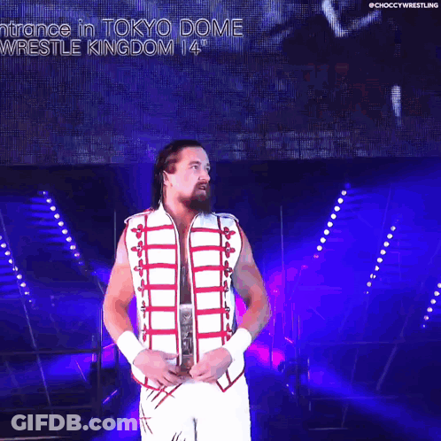 A Wrestler In A White And Red Outfit Is Holding A World Heavyweight Wrestling Championship Belt GIF