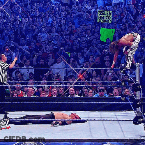 A Wrestler In A Wrestling Ring Holds A Sign That Says Zelen Amigo Yondy GIF