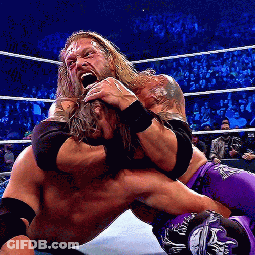 A Wrestler In Purple Shorts Is Wrestling Another Wrestler In A Ring GIF