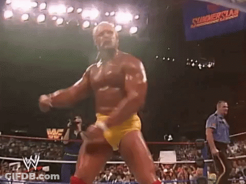 A Wrestler In Yellow Shorts Is Dancing In A Wrestling Ring In Front Of A Crowd . GIF