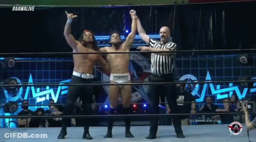 A Wrestler Is Being Congratulated By Another Wrestler In The Ring GIF