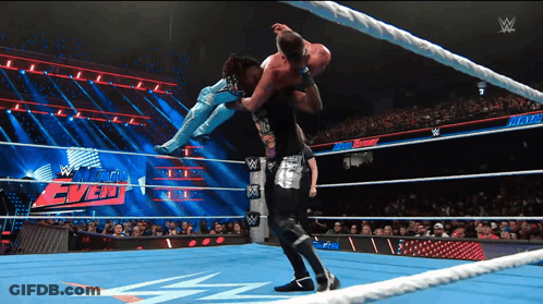 A Wrestler Is Being Lifted In The Air By Another Wrestler During A Match GIF