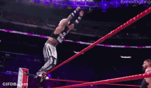 A Wrestler Is Being Lifted In The Air By Another Wrestler In A Ring . GIF