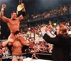 A Wrestler Is Carrying Another Wrestler On His Shoulders In A Ring GIF