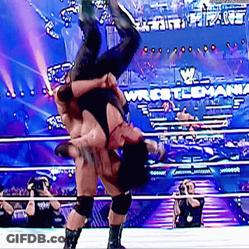 A Wrestler Is Doing A Flip Over Another Wrestler In A Wrestling Ring GIF