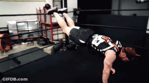 A Wrestler Is Doing A Handstand In A Ring . GIF