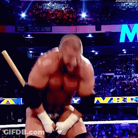 A Wrestler Is Holding A Baseball Bat In A Wrestling Ring With The Letter M In The Background GIF