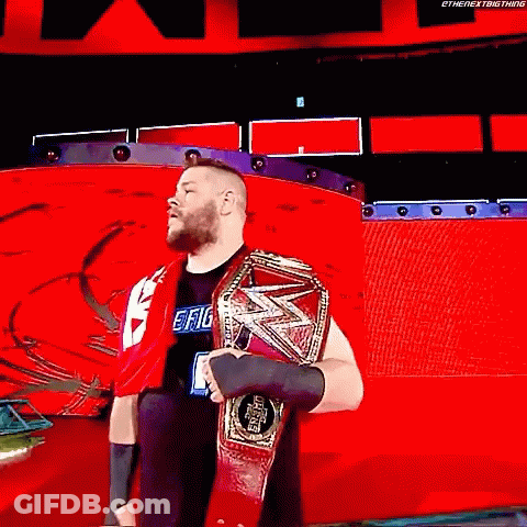 A Wrestler Is Holding A World Heavyweight Championship Belt While Standing On A Red Stage . GIF