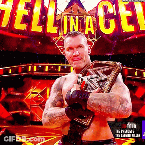 A Wrestler Is Holding A Wrestling Belt In Front Of A Sign That Says Hell In A Cell GIF