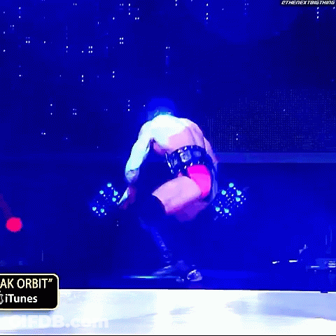 A Wrestler Is Jumping In The Air In Front Of A Sign That Says " Itunes " GIF