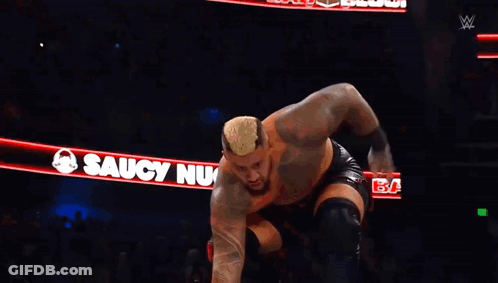 A Wrestler Is Jumping Over Another Wrestler In A Ring GIF