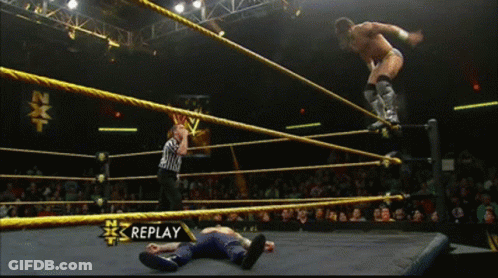 A Wrestler Is Jumping Over Another Wrestler In A Wrestling Ring With Replay On The Bottom Right GIF