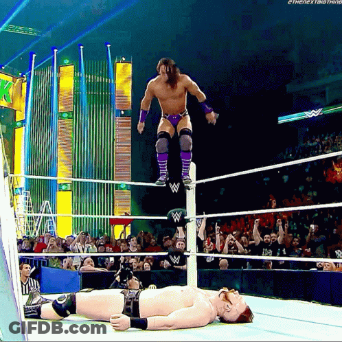A Wrestler Is Jumping Over Another Wrestler Laying On The Ground GIF