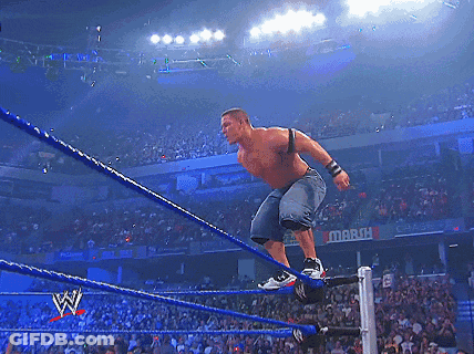 A Wrestler Is Jumping Over The Ropes In Front Of A Crowd With A Sign That Says March GIF