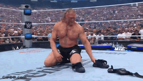 A Wrestler Is Kneeling Down In A Wrestling Ring That Says The Reigns On It GIF