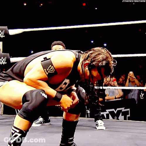 A Wrestler Is Kneeling Down In A Wrestling Ring While A Crowd Watches GIF