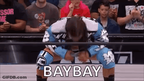 A Wrestler Is Kneeling Down In Front Of A Crowd And The Word Baybay Is Written On The Screen . GIF