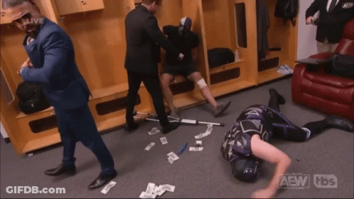 A Wrestler Is Laying On The Floor In A Locker Room With The Aew Logo On The Bottom Right GIF