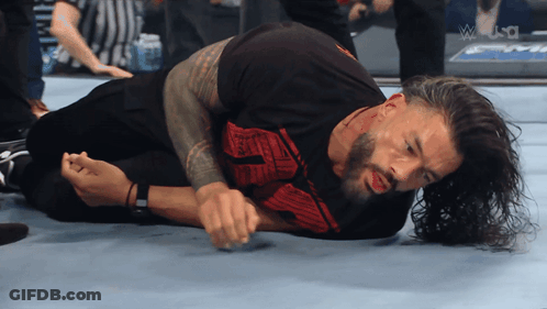 A Wrestler Is Laying On The Floor With The Word Wrestle In The Corner GIF