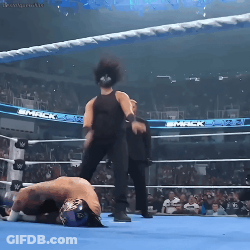 A Wrestler Is Laying On The Ground In A Wrestling Ring With The Words Mack Down On The Walls GIF